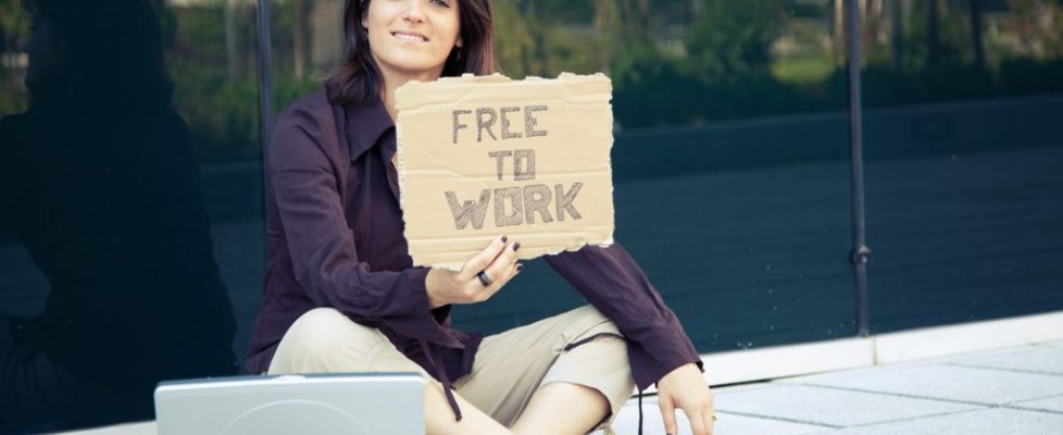 Professional woman sitting on sidewalk holding job search sign