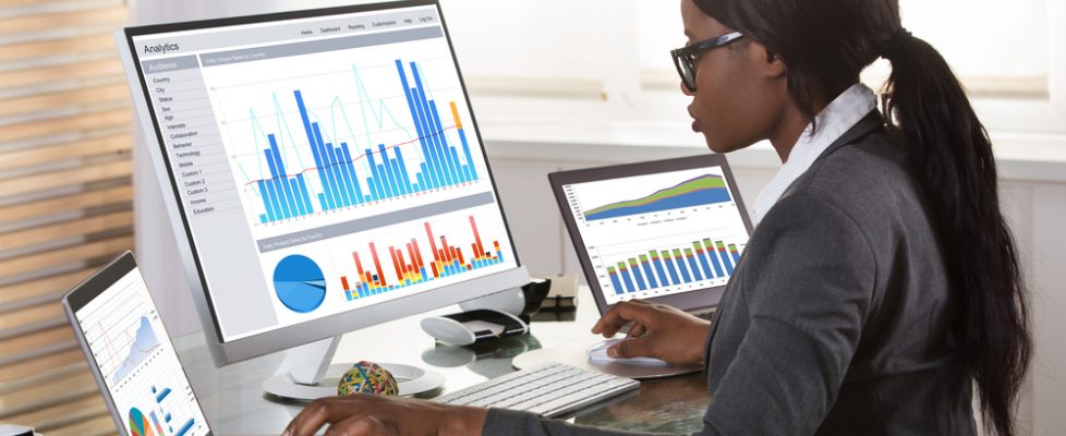 Young,African,Businesswoman,Looking,At,Graphs,On,Computer,In,Office